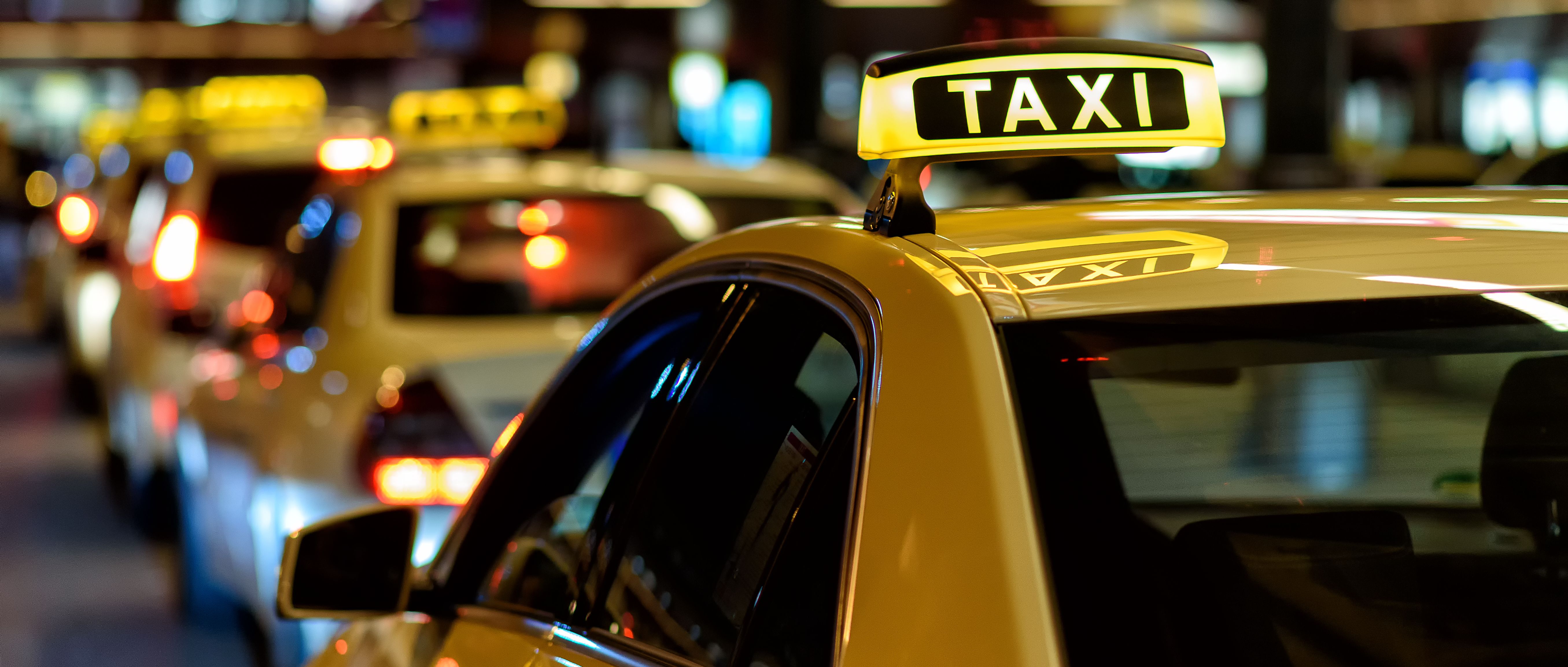 Eine Reihe gelber Taxis des Flughafentransfers in Bremen stehen hintereinander auf der Straße.